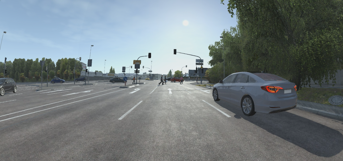 A junction on a sunny day with a silver car on the road